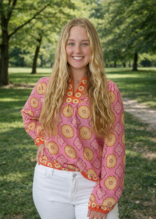 Woman wearing a pink patterned blouse standing in a park