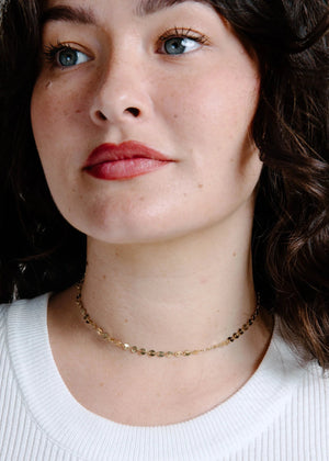 Woman wearing a gold necklace with a neutral background